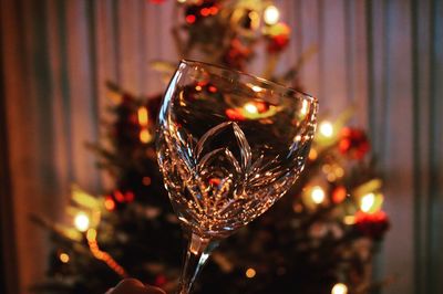 Close-up of wineglass against christmas tree at night