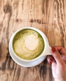 High angle view of hand holding tea cup on table