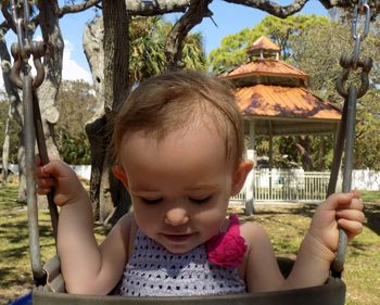 Close-up of cute girl playing on swing in park