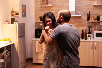 Side view of young woman drinking coffee while standing at home