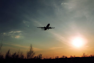 Low angle view of silhouette airplane against sky during sunset