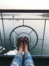 Low section of woman on pier over river against sky