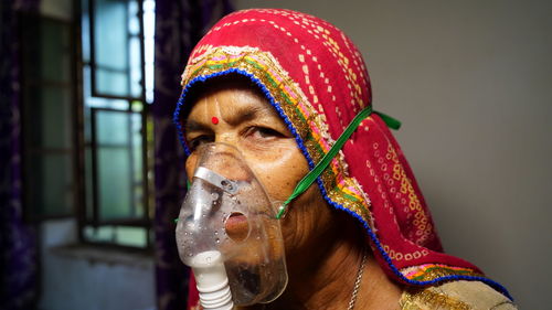 Close-up portrait of woman wearing oxygen mask at home