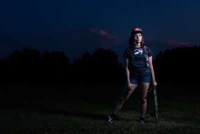 Full length portrait of young woman standing on field against sky