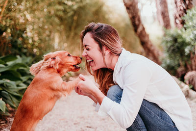 Midsection of woman with dog against trees