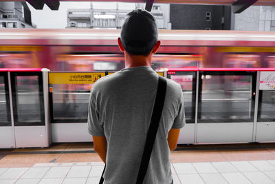 Rear view of man standing at railroad station