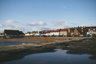 Houses by river and buildings against sky