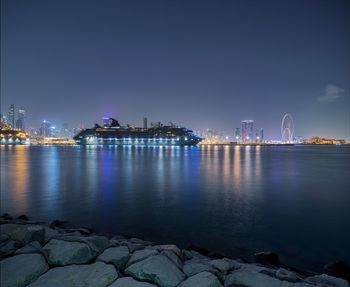 Illuminated buildings by sea at night