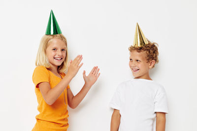 Cute sibling wearing party hat against white background