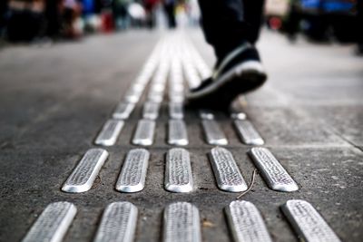 Low section of man walking on tactile paving in city