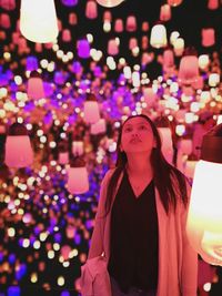 Portrait of woman standing against illuminated lights