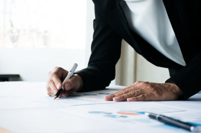Midsection of man holding paper at table