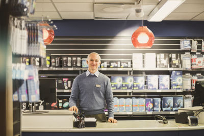 Portrait of smiling mature owner standing in electronics store
