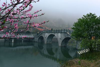 Bridge over river against sky during foggy weather