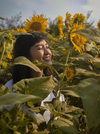 Young woman by sunflower on field