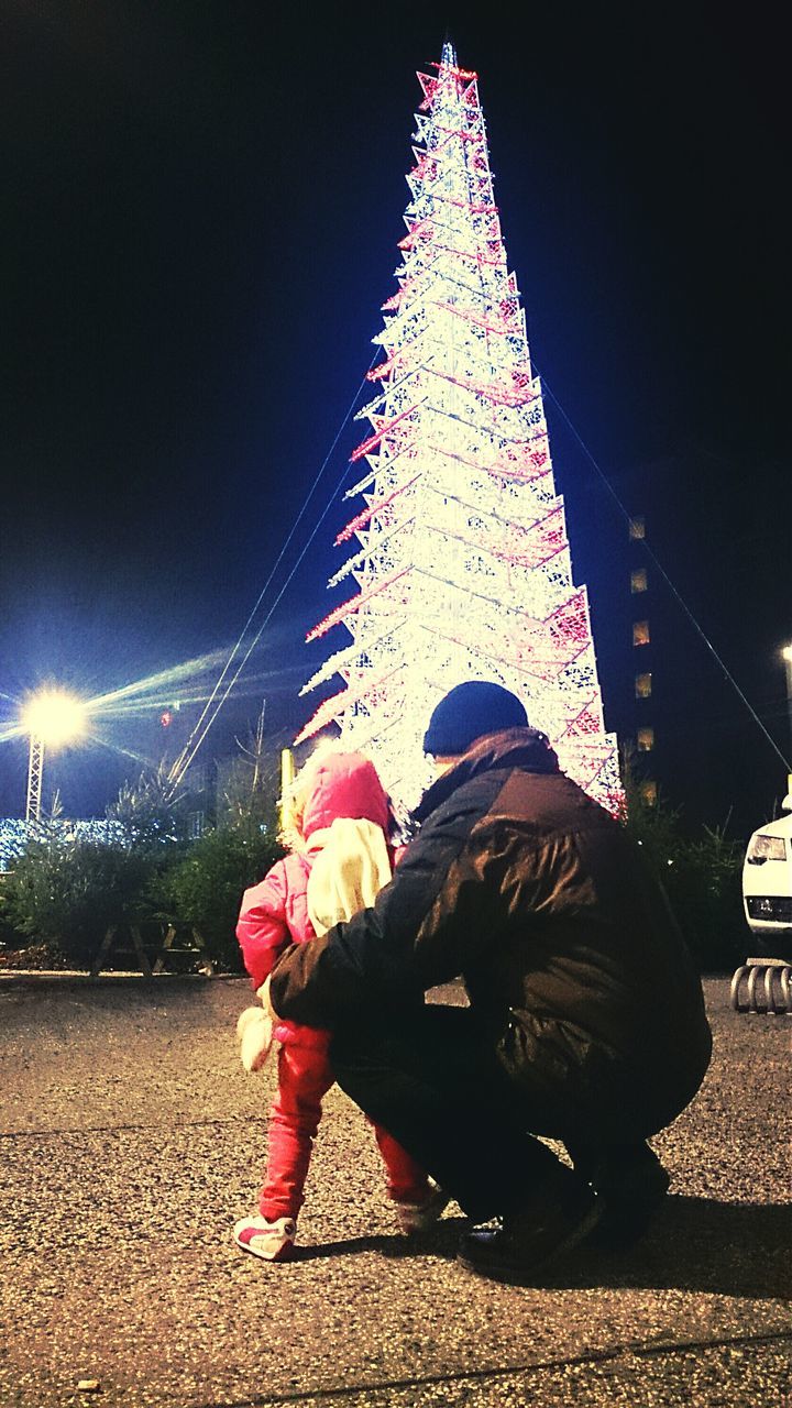 night, leisure activity, illuminated, lifestyles, arts culture and entertainment, rear view, motion, full length, person, men, casual clothing, celebration, standing, enjoyment, city, long exposure, built structure, architecture