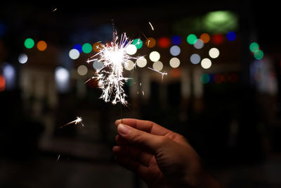 Hand holding illuminated lights at night
