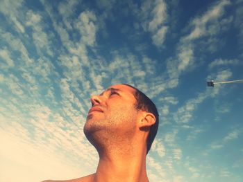 Low angle view of man looking up against cloudy sky