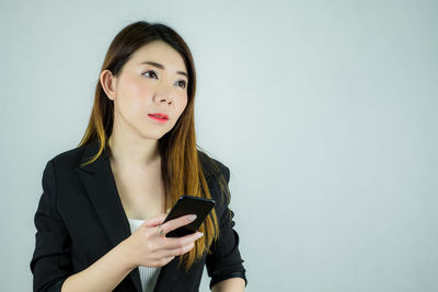 Portrait of young woman using smart phone against white background