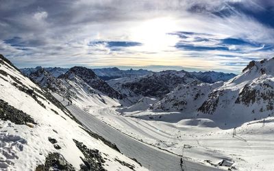 Scenic view of snowcapped mountains against cloudy sky