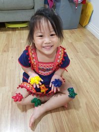 Portrait of cute girl smiling while sitting on floor at home