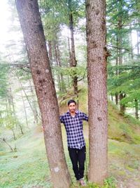 Full length portrait of smiling man standing in forest