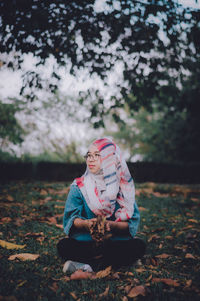 Woman wearing headscarf while sitting on field