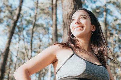 Portrait of young woman standing against trees