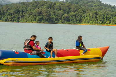 People on boat in lake against trees