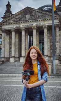 Portrait of smiling young woman standing on mobile phone