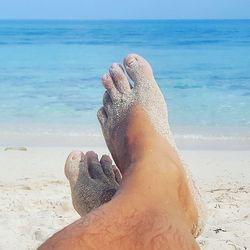 Low section of person on sand at beach