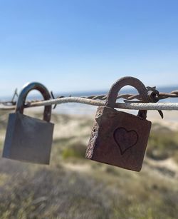 Close-up of padlocks on railing against sky