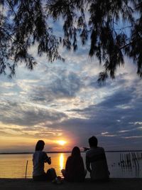 Silhouette people on beach against sky during sunset