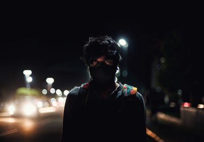 Portrait of young man standing on road at night