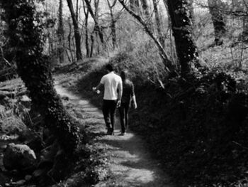 Rear view of woman walking on footpath in forest