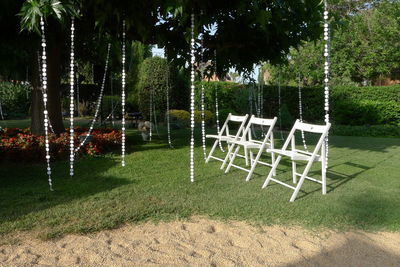 Empty chairs on grass against trees