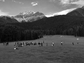 Group of people on land by mountains against sky