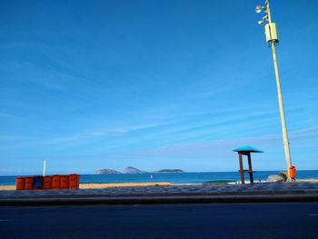 Road by sea against blue sky