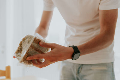 A young man holds a box with filler for planting wheat.