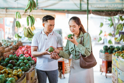 Portrait of smiling woman holding fruits at market