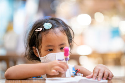 Portrait of cute girl holding table