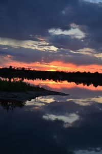 Scenic view of lake against dramatic sky during sunset