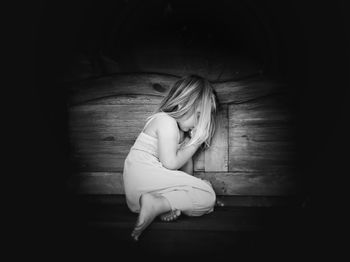 Side view of a young woman sitting on floor