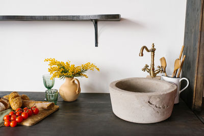 Retro stone sink and mixer golden in the kitchen in the scandinavian style, a bouquet of mimosa 