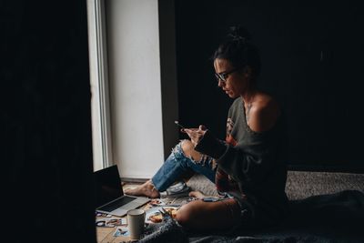 Woman using mobile phone while siting at home