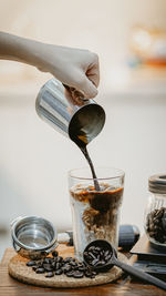 Cropped hand of person pouring coffee on table