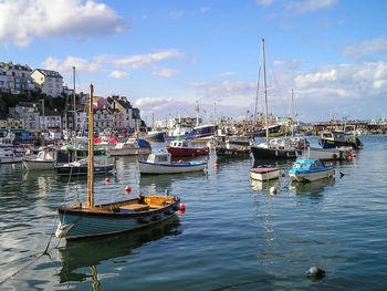 Boats moored at harbor against sky