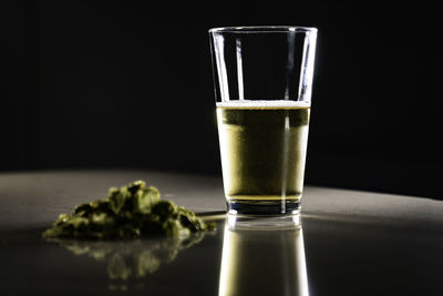 Close-up of beer in glass by marijuana on table