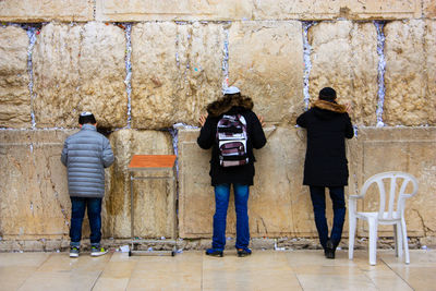 Rear view of men standing against wall