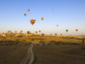 Hot air balloons flying over landscape against clear blue sky